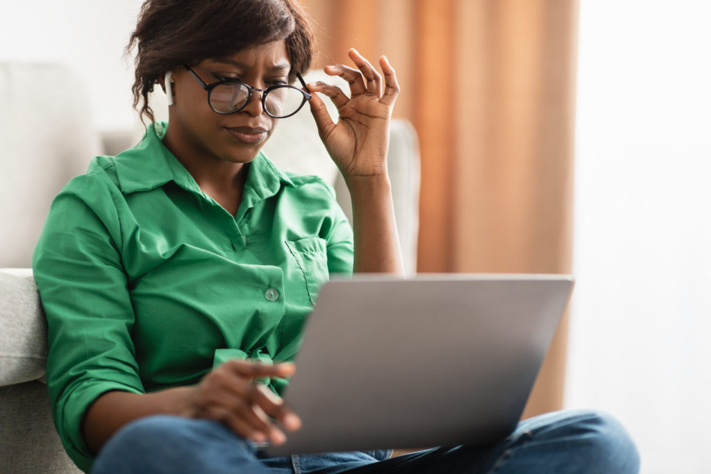 Mulher de camisa verde olhando os critérios de análise de fornecedor de serviço no seu notebook.